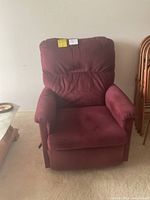 Front view of the burgundy rocker recliner chair with cushioned arms and back.