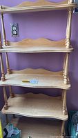 Full view of the 5 tier wooden shelf showing front and side, highlighting the turned wooden supports and curved shelf edges.