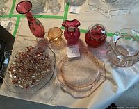 Seven pieces of pink Depression glass including three vases, multiple bowls, a plate, and a glass bowl with assorted clear and pink glass beads on a table.