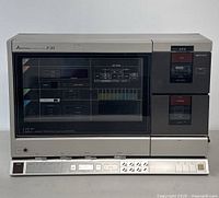 Front view of the Mitsubishi Z20 vertical cassette deck showing the large vertical cassette slot, radio tuner display, and control buttons along the bottom panel.