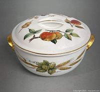 Front view of lidded bowl featuring peach branch design on lid and gold handles on bowl sides