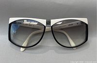 Front view of sunglasses showing black and white frame with gradient lenses