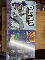 Top view photo showing front of Dog Man Attack of the Fleas and I Spy Spooky Mansion boxed games.