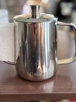Side view of the stainless steel tea pot showing polished exterior and handle, with brand name 'Wingui' visible.