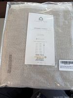 Clear image of new Central Park sheer curtain grommet panels folded inside original packaging with visible product label showing size and certification.