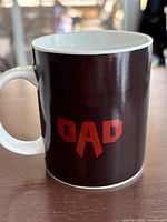Photo of the white ceramic mug showing the word "DAD" in large red letters on a black background
