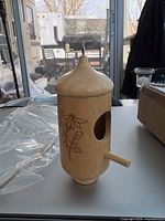 Wooden hummingbird house on a table with a patio scene in the background