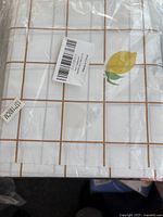 Folded lemon theme table cloth in clear packaging showing grid lines and lemon prints.