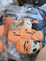Four plush dog keychains dressed in orange pumpkin costumes vacuum packed in clear plastic.