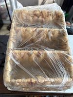 Rectangular woven remote holder with three compartments, photographed from above showing woven texture and plastic wrap.