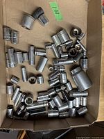 Photo of a box with various used metal sockets of different sizes and types including deep and shallow sockets in metric and SAE standards.