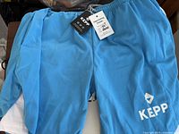Photo showing a pair of large blue Kepp athletic shorts with attached tags and Kepp logo on left leg.