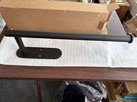 Black stainless steel paper towel rack taken out of the box on a table with some packaging visible.