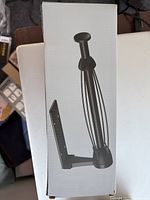 Photo of the unopened box showing an image of the black metal under cabinet paper towel holder.