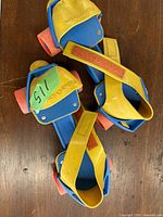 Top view of the two vintage Fisher Price kids roller skates showing blue footbeds, yellow Velcro straps, and orange wheels with slight wear