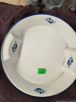 Top-down photo of a large vintage ceramic bowl showing white base and blue floral decorations on the rim.