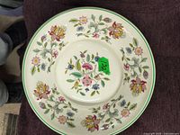Top view image showing round serving dish with floral pattern of multicolor flowers and green leaves, green trim on edge and center