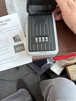 Photo showing the open key safe with four-digit dials set to factory code and instruction manual.
