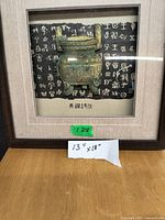 Framed wall picture with Asian-inspired ceremonial vessel and Chinese characters, measuring 13 by 13 inches.