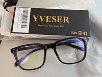 Black rectangular frame computer glasses with slightly yellow tinted lenses on a white surface, accompanied by a YVESER branded black box with gold text.