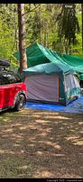 Fully assembled green and gray tent at campsite under green tarp