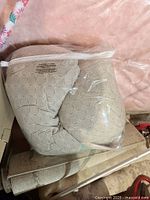 Photo of the pregnancy pillow inside clear plastic packaging showing beige cover with geometric circle pattern.