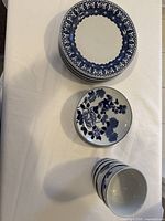 Stack of dinner plates with floral border design, smaller dessert plate with floral pattern, and bowls with blue floral exterior.