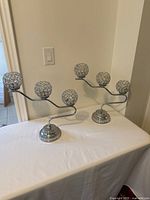 Two silver-tone candelabras side by side, each with 3 spherical crystal studded candle holders