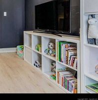 White IKEA Kallax storage unit in use with toys and books inside; flat surface shows minor dent on side.