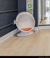 Photo showing white and red IKEA kids swivel chair with astronaut style hood against a dark wall and light flooring.