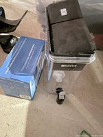 Front view of XL Brita water filter with black lid and visible spout, next to unopened box of replacement filters.