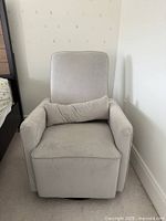 Front view of the light gray swivel recliner chair with lumbar pillow on seat.