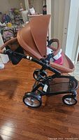 Side angle of Mima Xari stroller showing camel leather accents and black frame