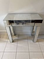 Front view of mirror console table showing single drawer with knob and mirrored legs