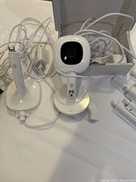 Nanit baby monitor camera, wires, stand, and wire covers laid out on a flat surface.