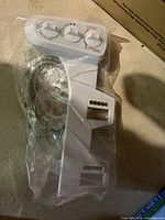 Mechanical bidet attachment with manual control knobs and connection hoses, sealed in plastic bag