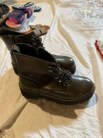 Side and front view of the olive green leather combat boots showing platform sole and black zipper closure.