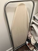 Full view of the ironing board with beige fabric cover, showing the metal frame and ironing surface.