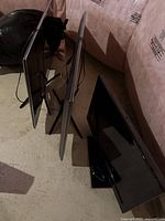 Three Samsung TVs placed upright on a floor with clear view of screen sides and stands.