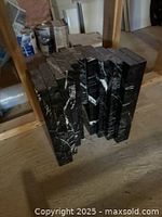 Top/front view of stacked solid black granite slabs on a wooden floor, showing thickness and texture.