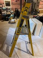 Large Keller step ladder side view showing yellow paint, metal steps, and caution markings