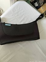 Photo of black Uppababy stroller caddy lying flat showing its exterior with Uppababy tag on the side.