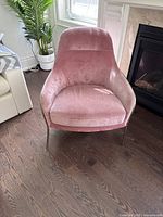 Pink velvet West Elm accent chair with gold legs from a front angle showing curved back and cushion.