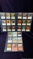 Front view of 27 Magic: The Gathering cards arranged in three sleeve sheets showing card art and layout from various editions.
