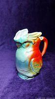 Front angle of the ceramic bird-shaped pitcher showing multicolor design and integrated handle.