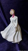 Front view of the Royal Doulton figurine named Mary showing the full figure in white dress and bonnet with pink ribbon.
