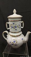 Full front view of the vintage porcelain teapot with infuser, showing floral blue flowers and gold trim on white porcelain