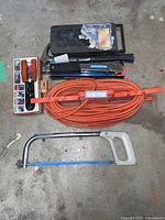 Overview of assorted electrical and hand tools including extension cord, wire stripper, staple gun and hacksaw