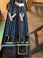 Blue metal folding saw horses showing hinges and foldable legs for storage.