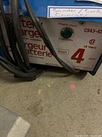 Close-up of front panel of Sears battery charger showing polarity check light, 4 amp rating, and model number C943-476.